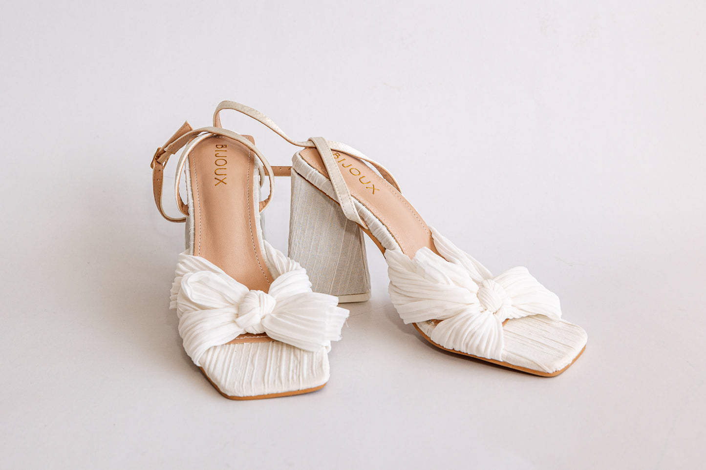 Pair of white chiffon peep toe heels with bow detail, ankle strap and triangle block heel
